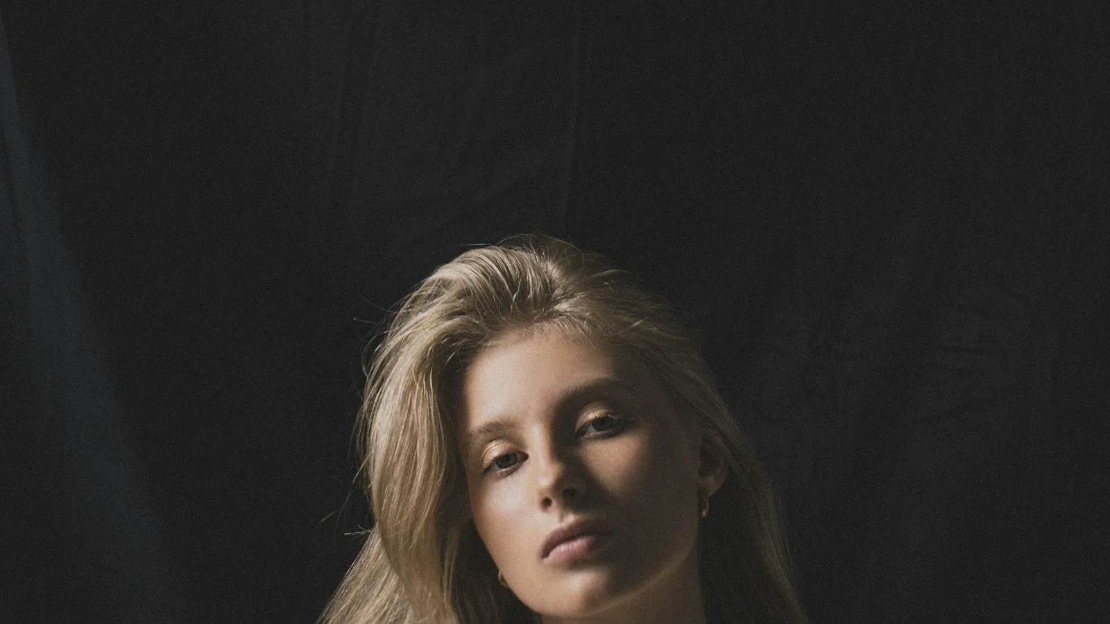 Professional business portrait — woman in blazer, dramatic dark studio lighting