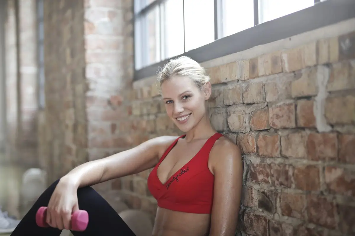Plavokosa žena s bučicom u teretani — fotografija za fitness centre i osobne trenere Zagreb