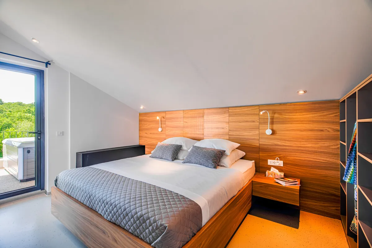 Casa Meline penthouse bedroom — attic apartment with walnut headboard wall and terrace access