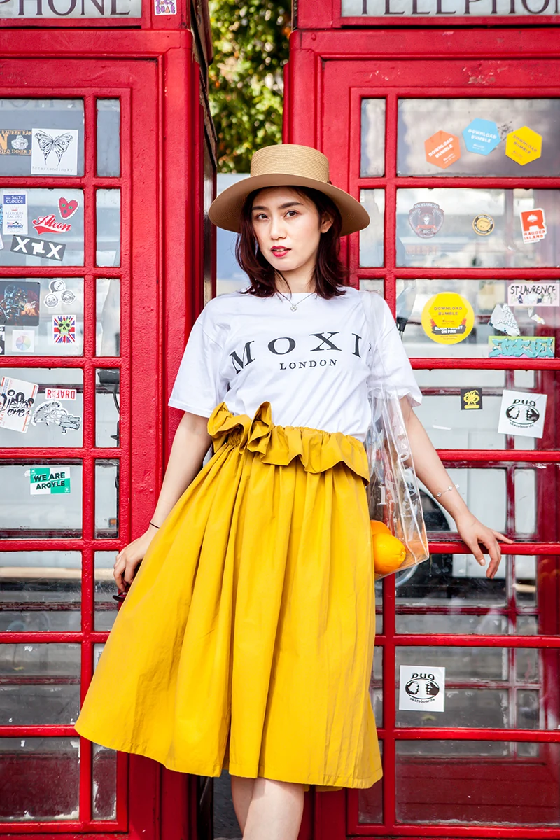 MOXI London fashion campaign — model in yellow skirt beside London red phone box, street editorial